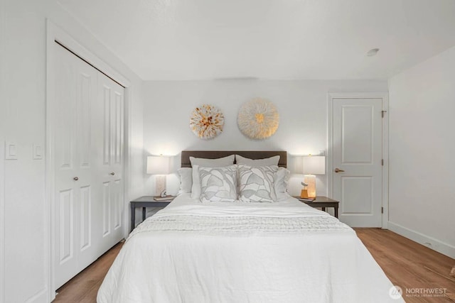 bedroom featuring wood finished floors, baseboards, and a closet