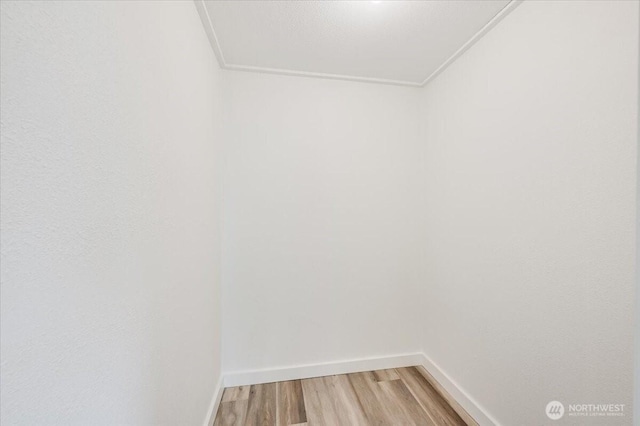 empty room with light wood-type flooring, ornamental molding, and baseboards