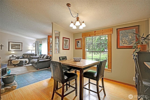 472 Iris Ln, Camano Island, WA 98282 - dining room featuring a chandelier, light wood-style flooring, lofted ceiling, crown molding, and a textured ceiling