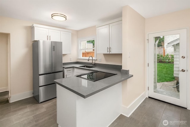 816 N 43rd St, Seattle, WA 98103 - kitchen with freestanding refrigerator, a sink, black electric cooktop, white cabinets, and baseboards