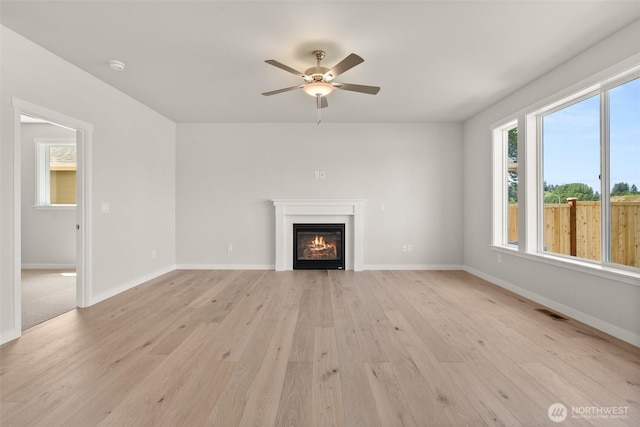 2880 75th Ave SW Lot 62, Tumwater, WA 98512 - unfurnished living room with light wood-style flooring, a glass covered fireplace, a ceiling fan, and plenty of natural light