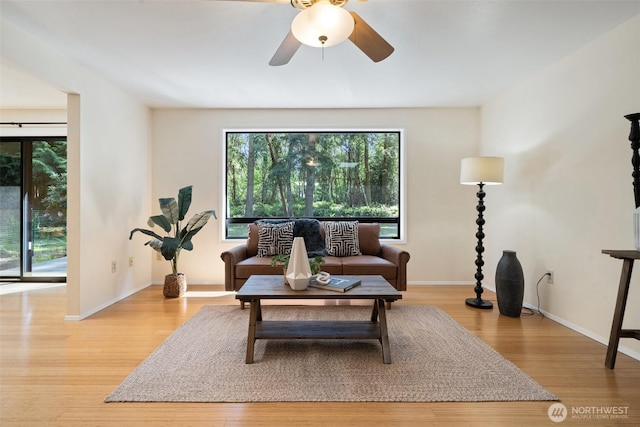 living room featuring plenty of natural light, a ceiling fan, baseboards, and wood finished floors