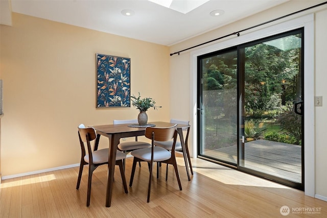 dining room with light wood-type flooring, a skylight, baseboards, and recessed lighting