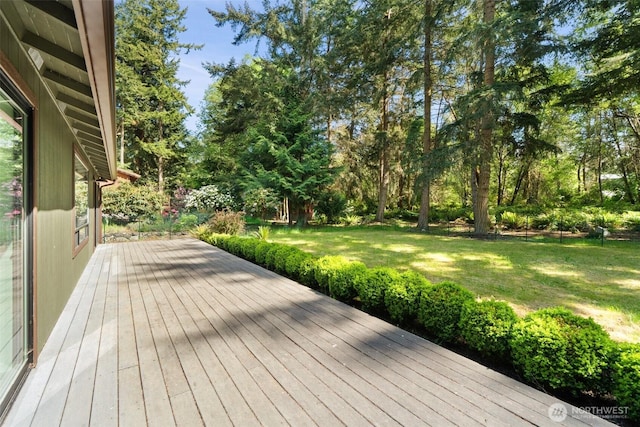 wooden deck with a lawn and view of wooded area