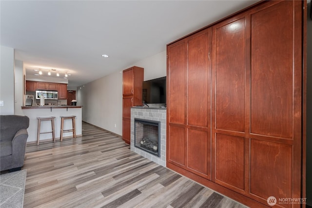 unfurnished living room featuring light wood-style floors, a fireplace, and track lighting