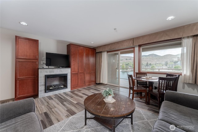 living area with light wood-type flooring, a brick fireplace, and recessed lighting