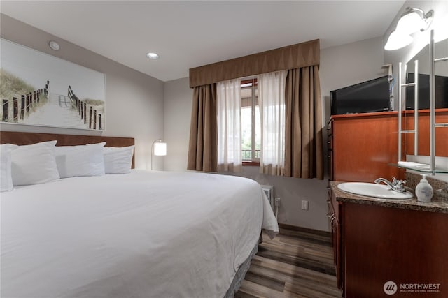 bedroom featuring dark wood finished floors, baseboards, a sink, and recessed lighting