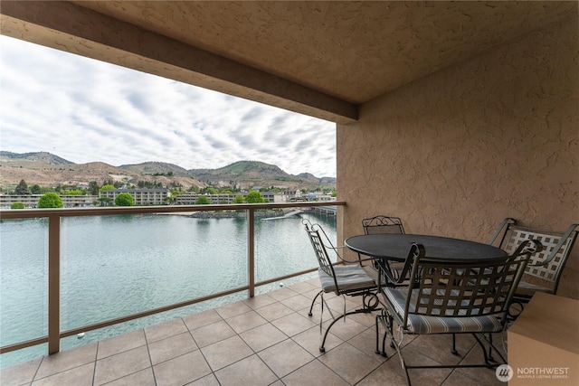 balcony with outdoor dining space and a water and mountain view