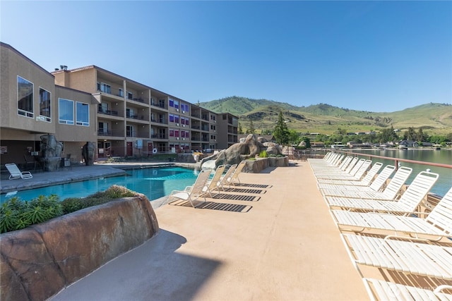 community pool with a mountain view and a patio