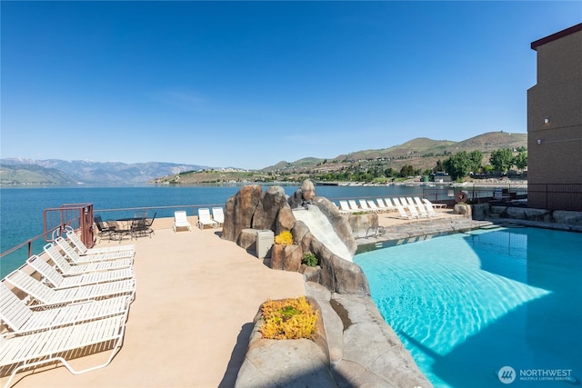 community pool with a water and mountain view and a patio area