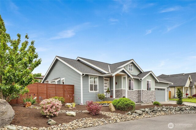 6068 Monument Dr, Ferndale, WA 98248 - view of front facade with board and batten siding, an attached garage, fence, stone siding, and roof with shingles