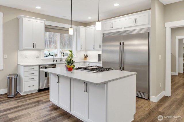6068 Monument Dr, Ferndale, WA 98248 - kitchen with appliances with stainless steel finishes, wood finished floors, white cabinets, a kitchen island, and recessed lighting