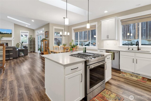 6068 Monument Dr, Ferndale, WA 98248 - kitchen featuring appliances with stainless steel finishes, a sink, wood finished floors, lofted ceiling, and light countertops