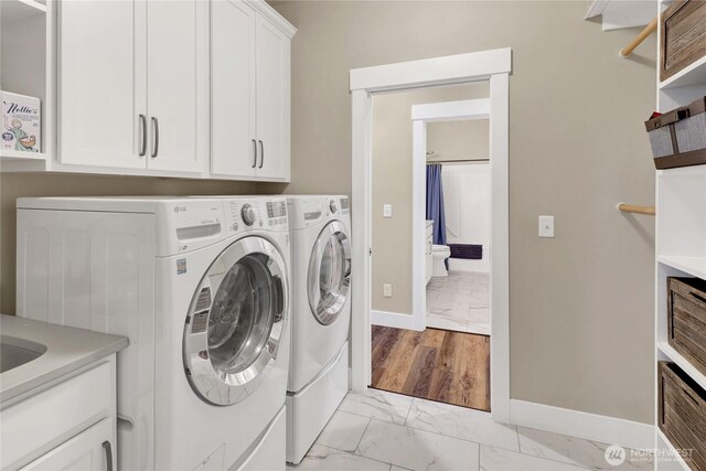 6068 Monument Dr, Ferndale, WA 98248 - laundry room with light marble finish floors, cabinet space, separate washer and dryer, and baseboards