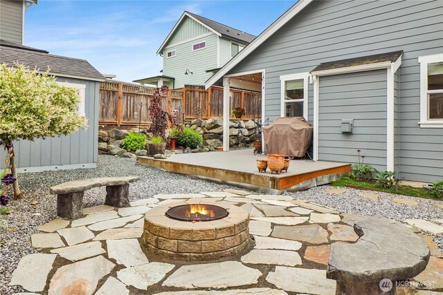 6068 Monument Dr, Ferndale, WA 98248 - view of patio with a fire pit, fence, a storage unit, a deck, and an outbuilding