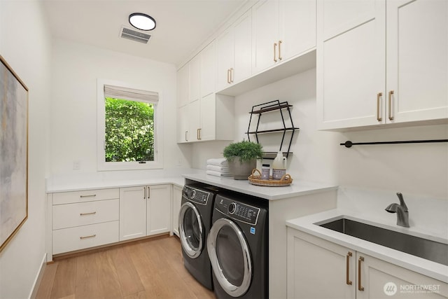 9234 NE 25th St, Clyde Hill, WA 98004 - laundry room with washer and clothes dryer, cabinet space, and light wood-type flooring