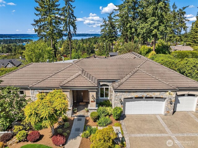 9234 NE 25th St, Clyde Hill, WA 98004 - single story home featuring stone siding, a tiled roof, driveway, an attached garage, and a water view