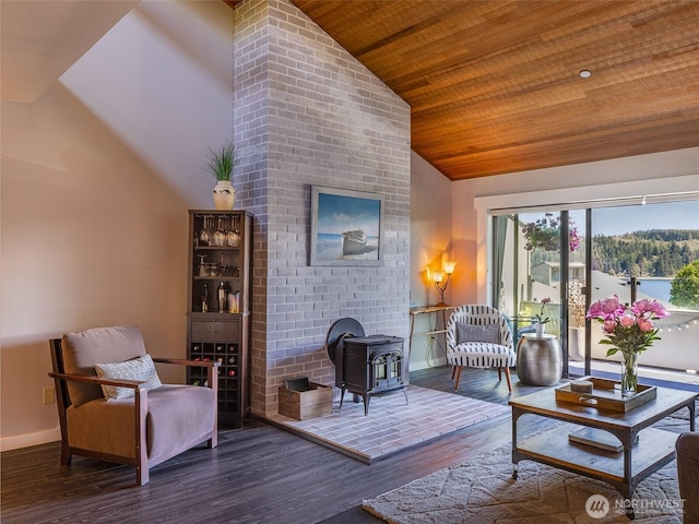living area featuring vaulted ceiling, wood ceiling, a wood stove, wood finished floors, and baseboards