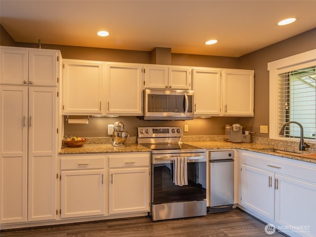 kitchen with appliances with stainless steel finishes, a sink, white cabinets, light stone counters, and recessed lighting