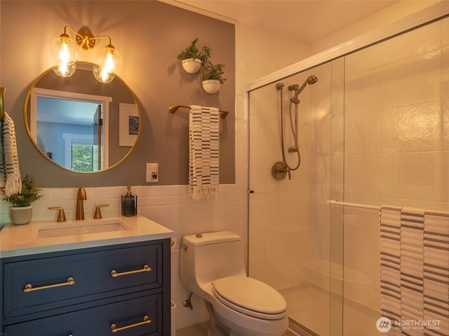 full bath featuring a stall shower, tile walls, vanity, and toilet