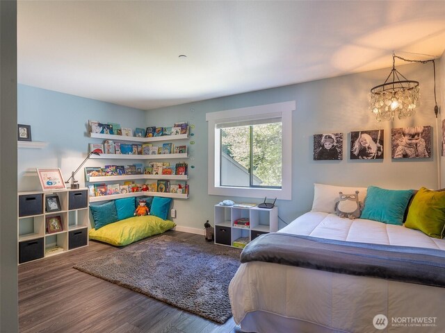 bedroom with a chandelier, wood finished floors, and baseboards