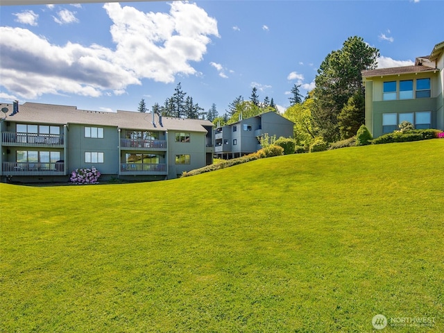 view of grassy yard featuring a balcony
