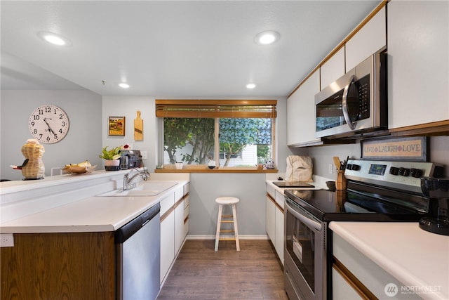 701 5th Ave S Unit C105, Kent, WA 98032 - kitchen with stainless steel appliances, a sink, a peninsula, white cabinets, and dark wood finished floors