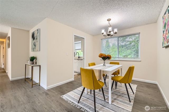 dining room with a chandelier, wood finished floors, a textured ceiling, and baseboards