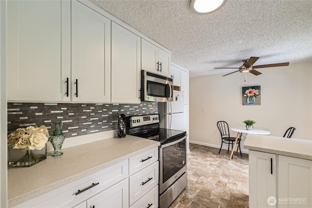 kitchen with stainless steel appliances, tasteful backsplash, a ceiling fan, light countertops, and white cabinets