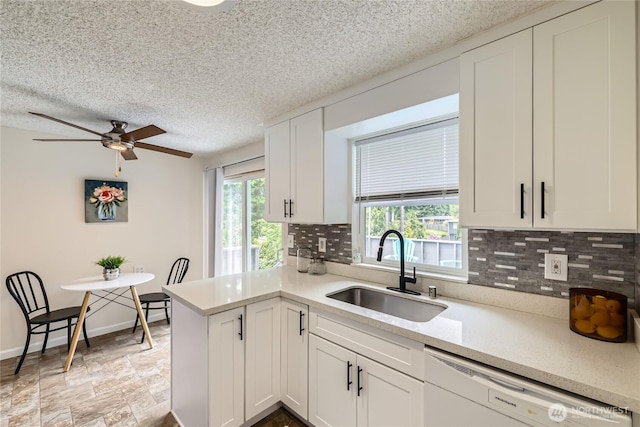 kitchen featuring a sink, dishwasher, decorative backsplash, white cabinetry, and a ceiling fan