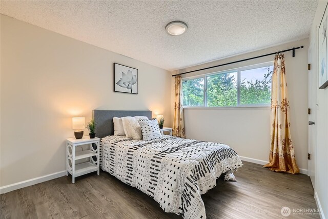 bedroom featuring wood finished floors, a textured ceiling, and baseboards