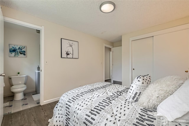bedroom featuring a closet, dark wood-style floors, connected bathroom, baseboards, and a textured ceiling