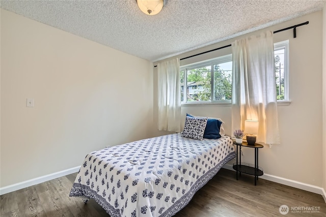 bedroom with baseboards, wood finished floors, and a textured ceiling