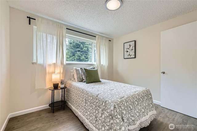 bedroom featuring wood finished floors, a textured ceiling, and baseboards