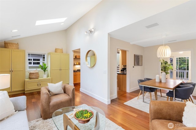living room featuring a skylight, vaulted ceiling, light wood finished floors, baseboards, and recessed lighting