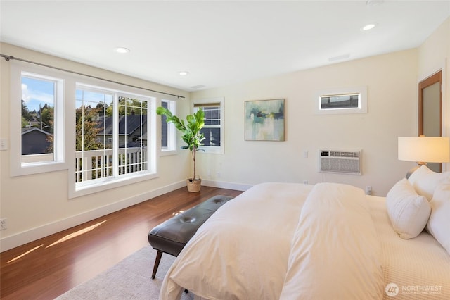 bedroom featuring wood finished floors, an AC wall unit, baseboards, and recessed lighting