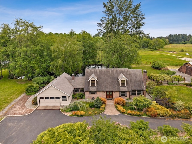view of front of home featuring a chimney, driveway, an attached garage, and brick siding