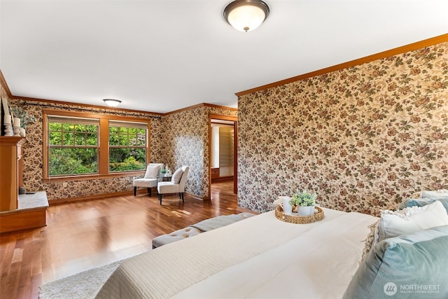 bedroom with wallpapered walls, crown molding, wood finished floors, and baseboards