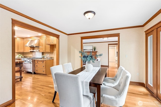 dining room with light wood-style floors, baseboards, and crown molding