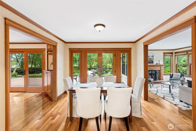 dining space featuring french doors, plenty of natural light, light wood-style flooring, and ornamental molding