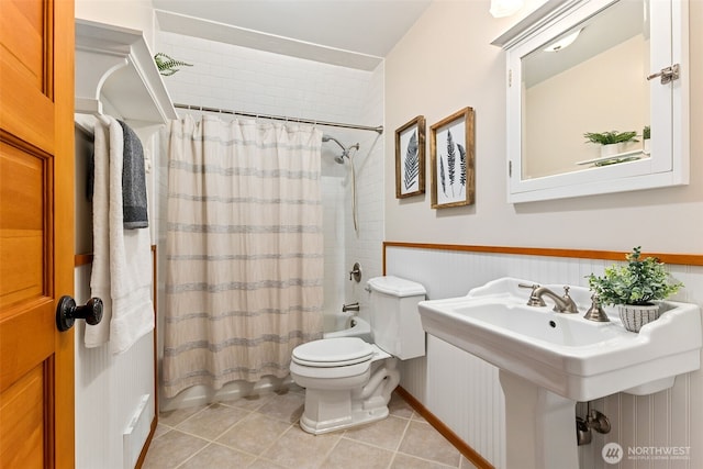 bathroom featuring wainscoting, tile patterned floors, toilet, and shower / bathtub combination with curtain