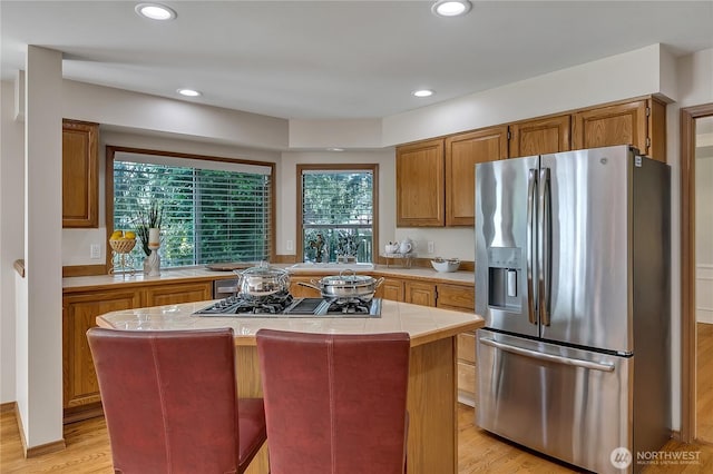8612 165th Street Ct E, Puyallup, WA 98375 - kitchen featuring appliances with stainless steel finishes, tile countertops, light wood finished floors, a kitchen island, and brown cabinetry