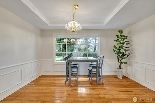 8612 165th Street Ct E, Puyallup, WA 98375 - dining space with a chandelier, a raised ceiling, a decorative wall, light wood-type flooring, and ornamental molding