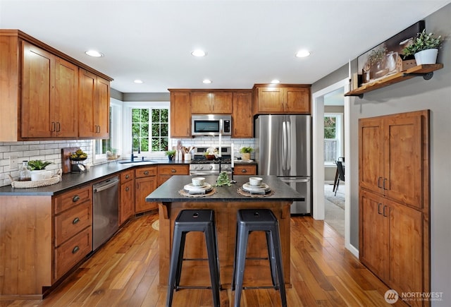 6423 138th Pl SE, Snohomish, WA 98296 - kitchen with stainless steel appliances, dark countertops, light wood-style floors, a breakfast bar, and decorative backsplash