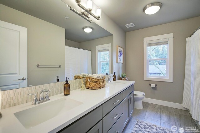 7223 NE 118th Ct, Kirkland, WA 98034 - bathroom featuring baseboards, double vanity, toilet, and marble finish floors