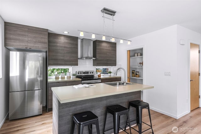 4757 Delridge Way SW, Seattle, WA 98106 - kitchen with stainless steel appliances, wall chimney range hood, a sink, a kitchen bar, and light wood-style floors