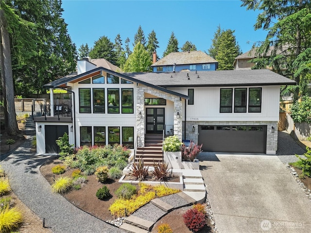 17905 NE 19th Pl, Bellevue, WA 98008 - view of front facade with driveway, stone siding, french doors, an attached garage, and roof with shingles