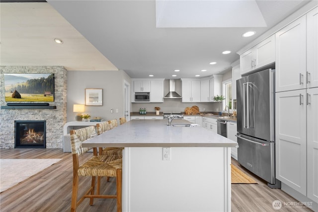 17905 NE 19th Pl, Bellevue, WA 98008 - kitchen featuring appliances with stainless steel finishes, wall chimney exhaust hood, a sink, a breakfast bar, and a stone fireplace