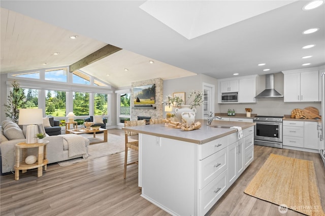 17905 NE 19th Pl, Bellevue, WA 98008 - kitchen with stainless steel appliances, wall chimney range hood, open floor plan, a stone fireplace, and light wood-style flooring