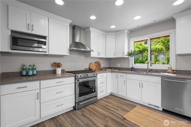 17905 NE 19th Pl, Bellevue, WA 98008 - kitchen featuring stainless steel appliances, wall chimney range hood, a sink, white cabinets, and recessed lighting